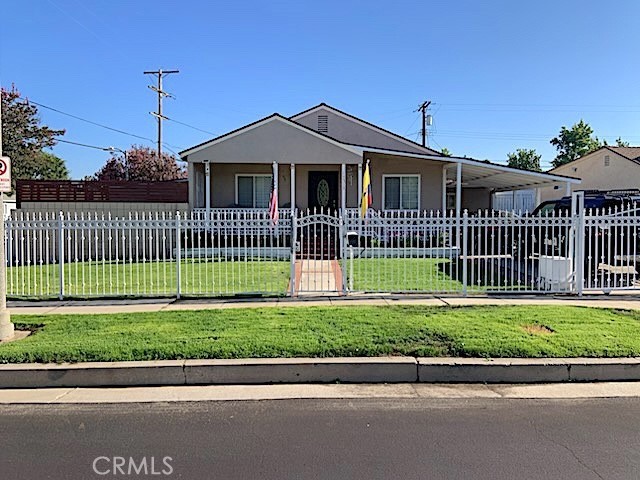 Front elevation of 17513 Tiara St, a single-story gray-stucco cottage with a columned covered porch behind a white picket and wrought-iron fence on a corner lot in Encino